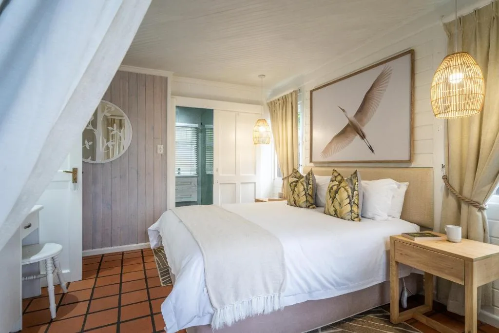 Spacious bedroom with queen bed, woven pendant lights, and coastal artwork