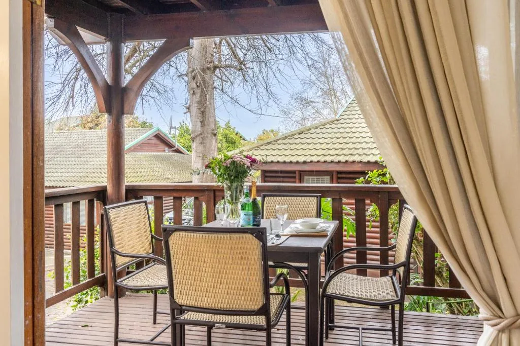 Wooden deck with dining table, chairs, and garden views overlooking neighboring properties