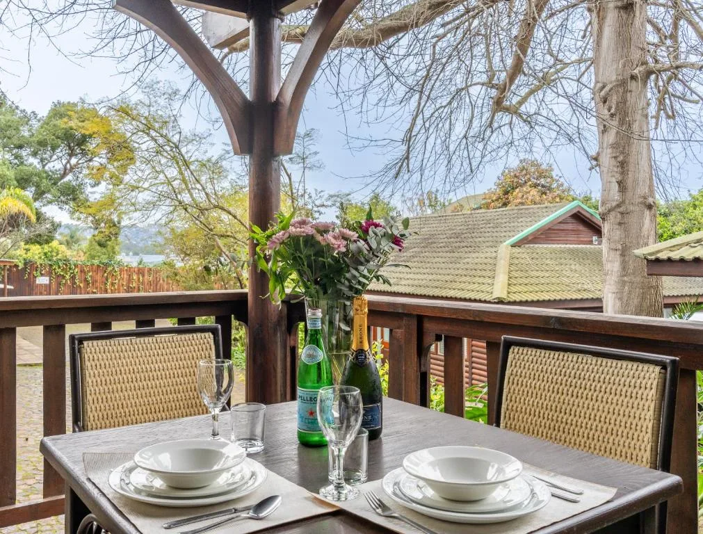 Outdoor dining setup with table, place settings, flowers, and scenic garden views