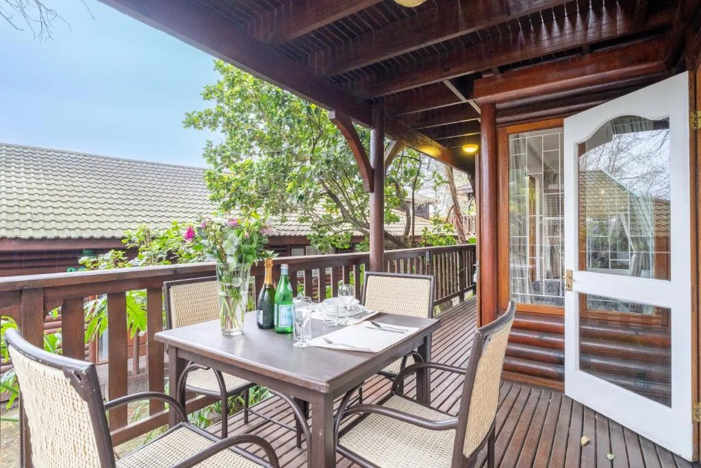 Covered wooden deck with dining table, chairs, and garden views