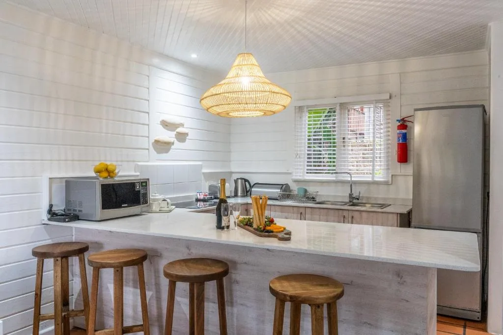 Modern kitchen with white cabinetry, stainless steel appliances, and wooden bar stools