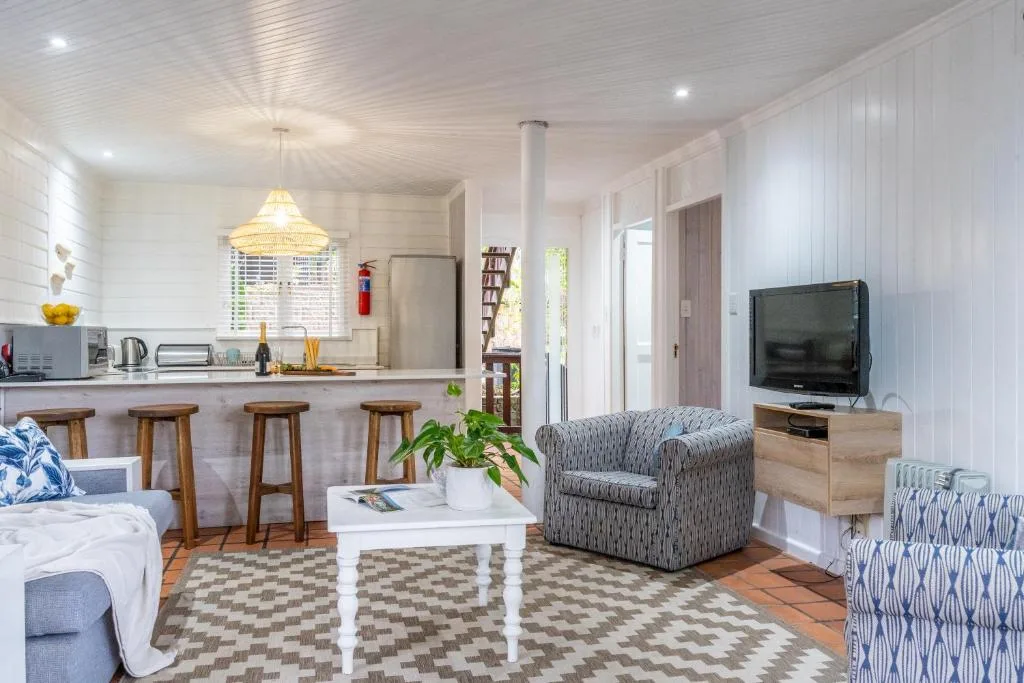 Open-plan lounge with patterned armchairs, TV, and kitchen bar seating