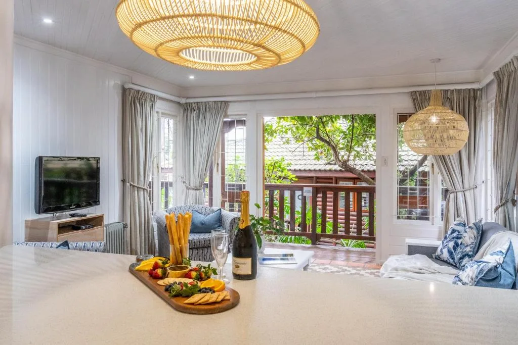 Open-plan lounge with TV, deck views, and elegant woven pendant lights