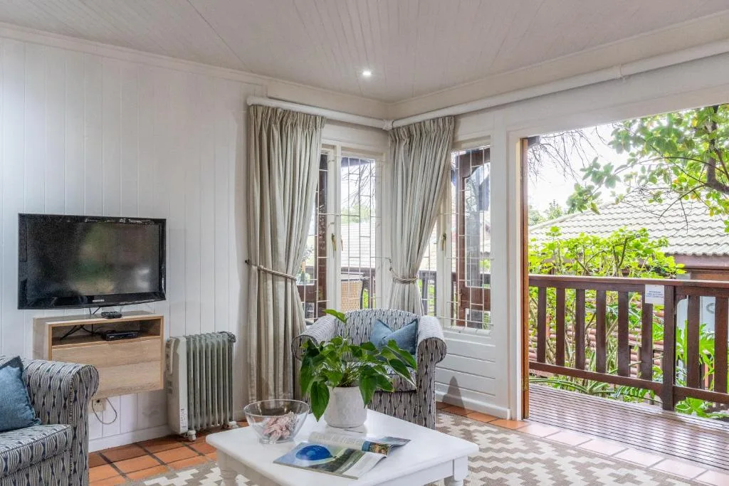 Bright lounge with TV, comfortable seating, and garden views through French doors