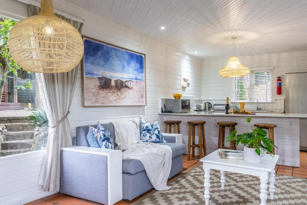 Bright open-plan lounge with gray sofa, woven pendant lights, coastal artwork