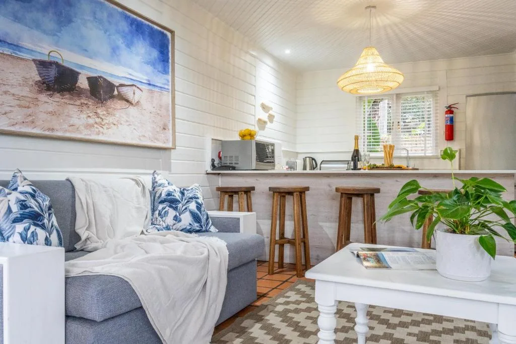 Open-plan lounge with gray sofa, kitchen counter, and coastal decor