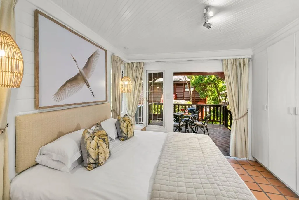 Bright bedroom with queen bed, deck access, and contemporary bird artwork