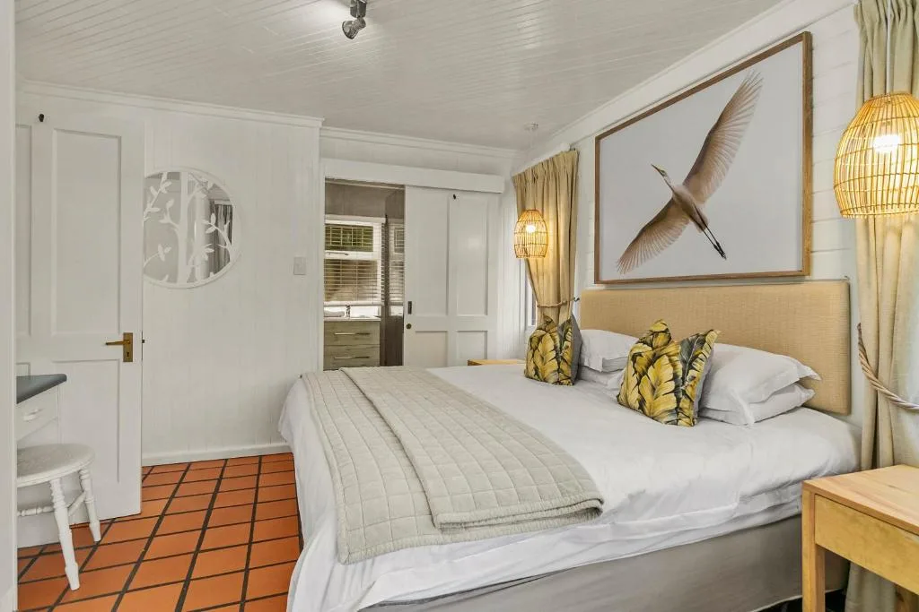 Spacious bedroom with queen bed, tan headboard, and bird artwork above