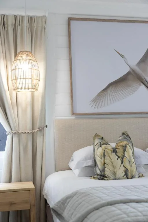 Bedroom with pendant lamp, framed bird artwork, and decorative pillows