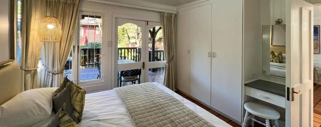 Spacious bedroom with queen bed, deck access, and garden views