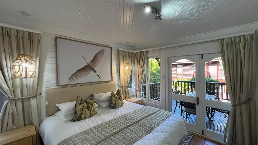 Bright bedroom with queen bed, deck access, and contemporary artwork
