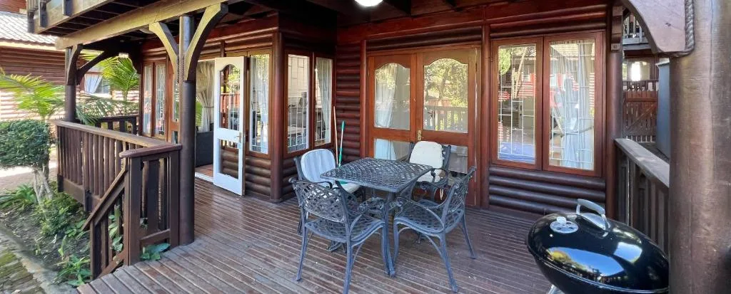 Wooden deck with outdoor furniture, braai grill, and garden views