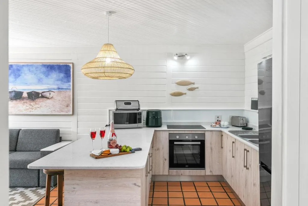 Modern kitchen with white cabinetry, island counter, and woven pendant light