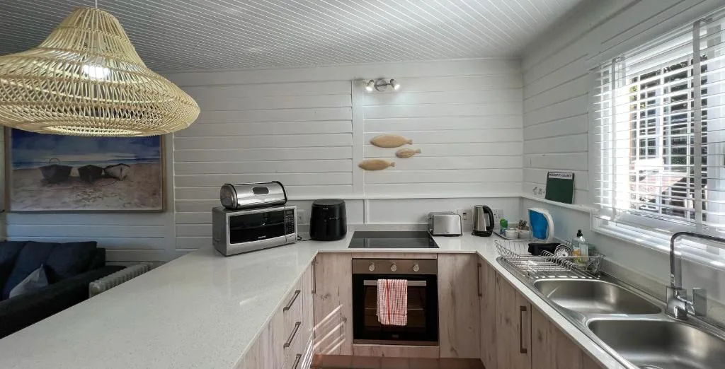 Compact kitchen with white counters, stainless steel sink, and modern appliances
