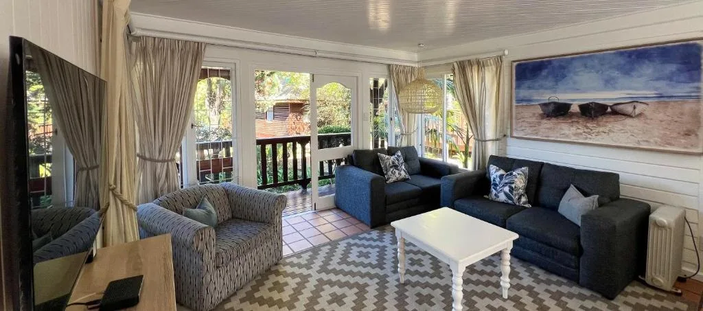 Bright lounge with dark sofas, striped armchair, white coffee table, and garden views