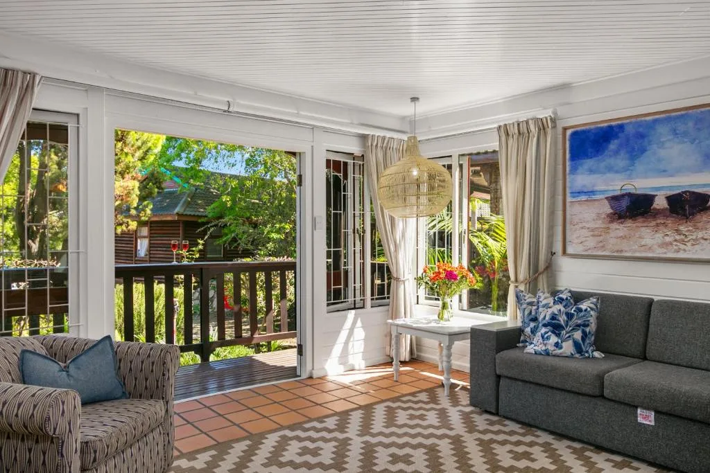 Bright lounge with gray sofa, striped chairs, and access to wooden deck