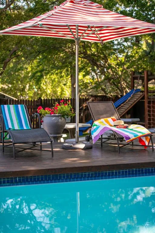 Swimming pool with colorful umbrella and lounge chairs on wooden deck