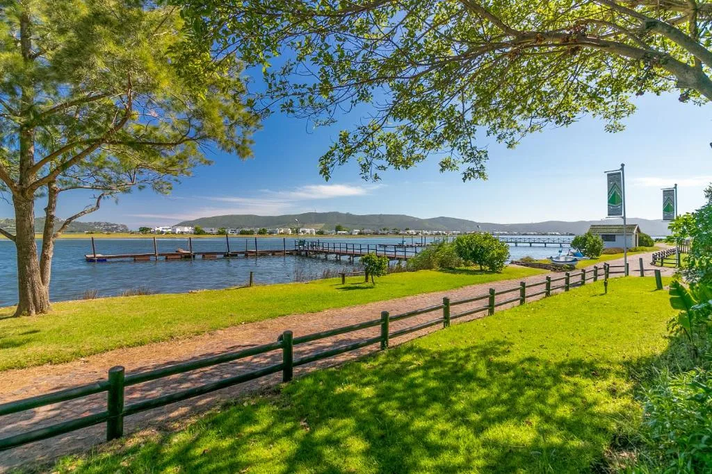 Scenic lagoon view with jetty, mountains, and lush green gardens