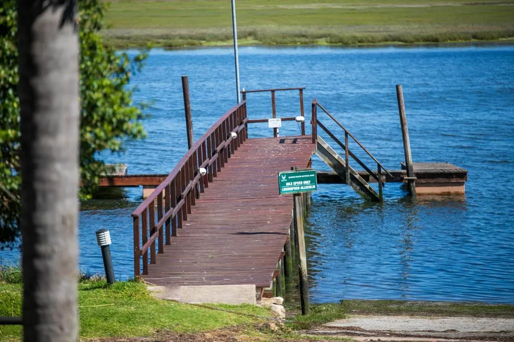 Wooden jetty extending into bright blue lagoon water with green banks