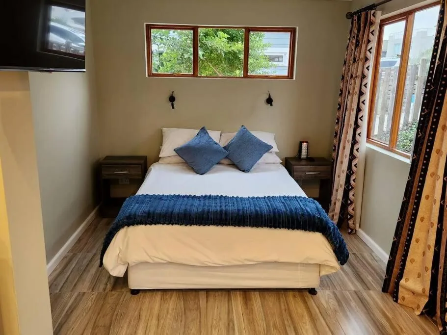 Bedroom with queen bed, blue cushions, wooden nightstands, and garden views