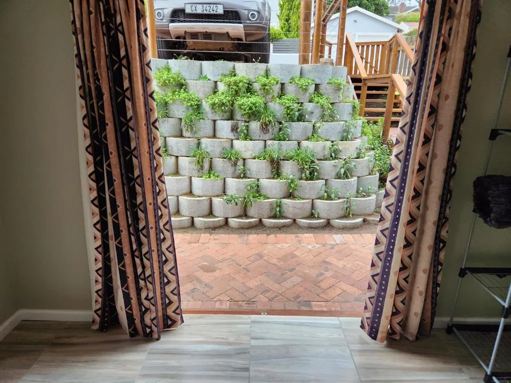 Open doors reveal tiered succulent garden wall and brick patio outside