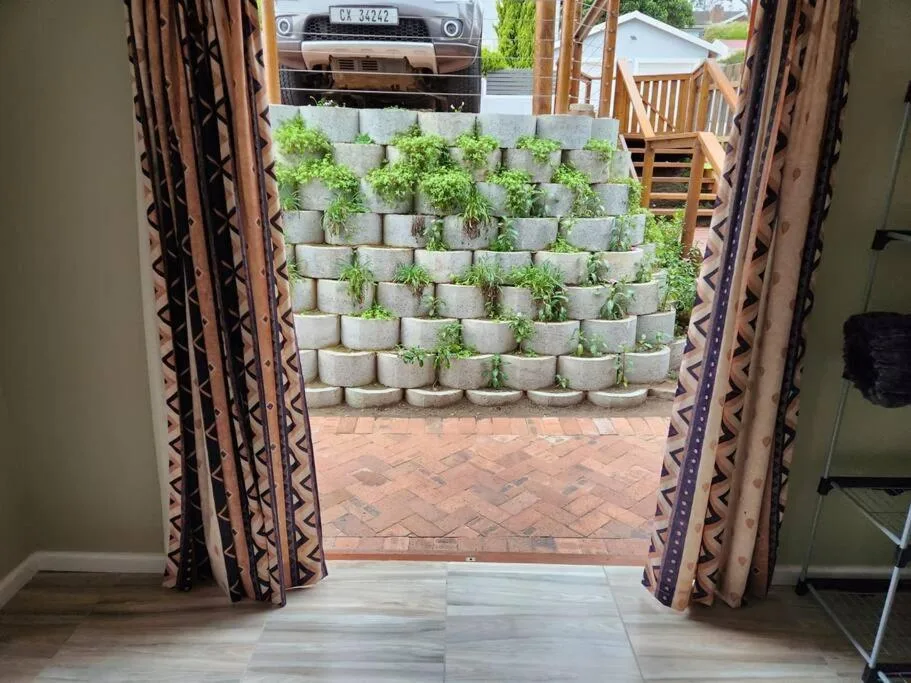 View through open doors to brick patio with stacked planter wall and parked vehicle