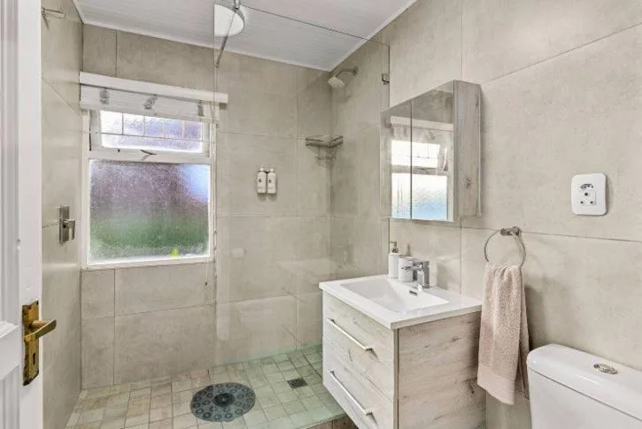 Modern bathroom with walk-in shower, vanity sink, and garden window views