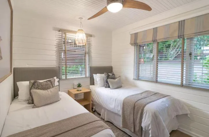 Bright twin bedroom with white bedding, grey accents, ceiling fan