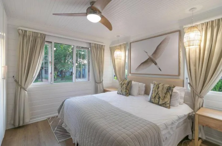 Bright bedroom with queen bed, cream curtains, and garden views