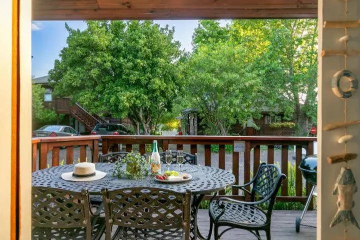 Outdoor deck with round table, chairs, and scenic tree-lined views beyond