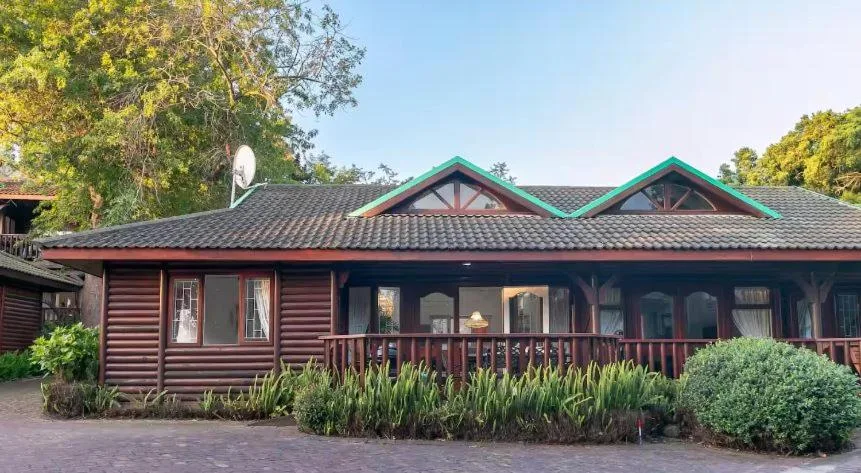 Red timber chalet with pitched green roof and front wooden deck