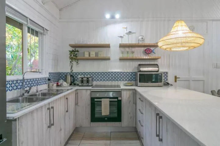 Modern kitchen with white cabinetry, green oven, and woven pendant light