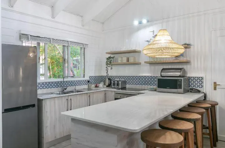 Modern kitchen with white cabinetry, patterned backsplash, and woven pendant lights