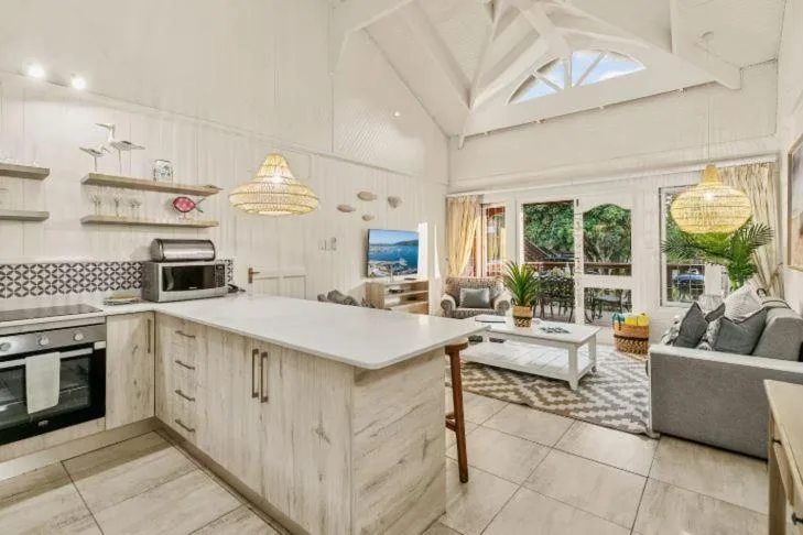 Bright open-plan living space with kitchen island, sofa, and garden views
