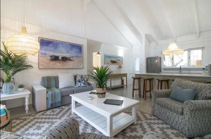 Bright open-plan lounge with coastal decor, comfortable seating, and ocean artwork