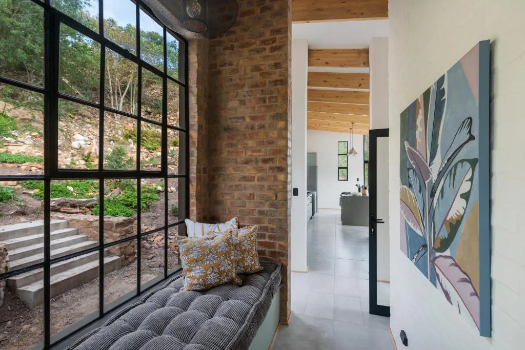 Modern lounge with window seat overlooking natural landscape and garden views