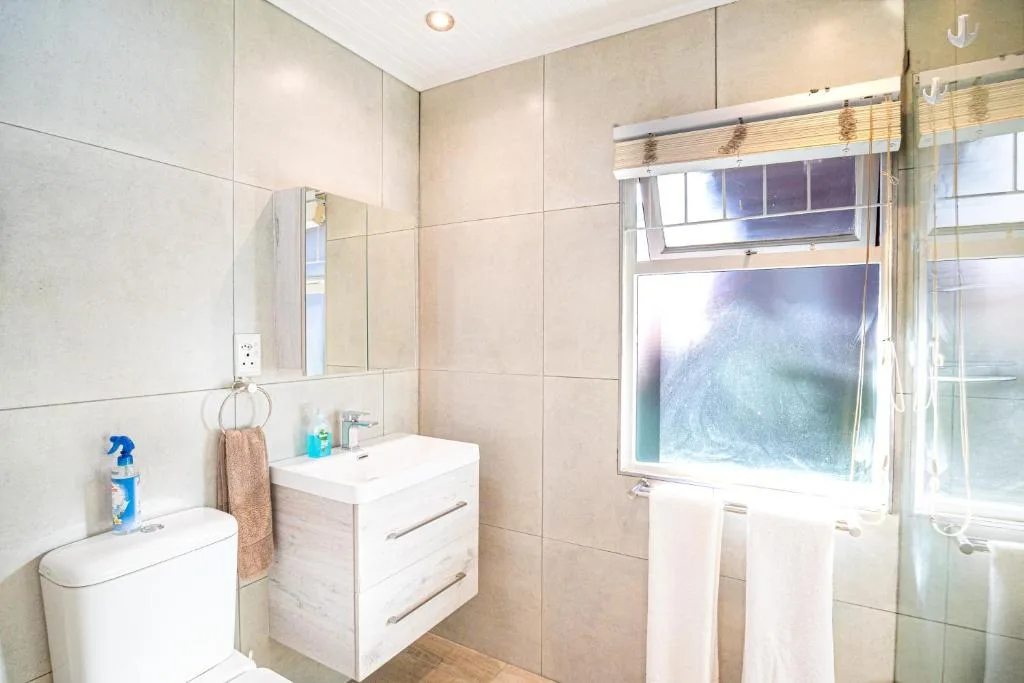 Modern bathroom with toilet, vanity sink, and glass-enclosed shower area