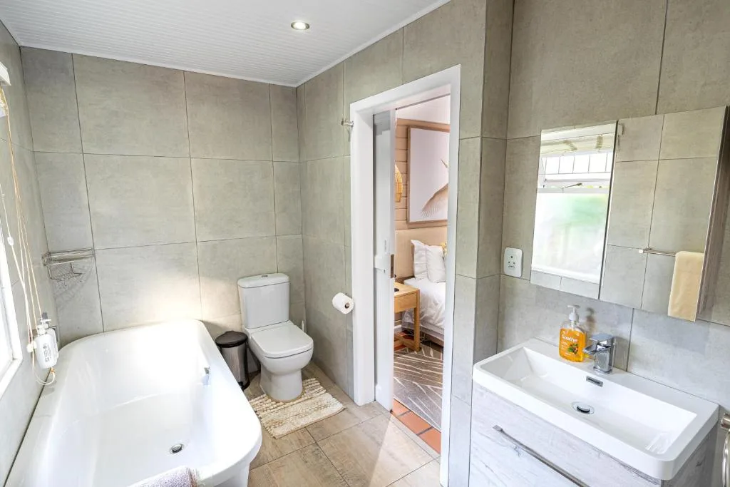Modern bathroom with bathtub, toilet, vanity sink, and tiled walls