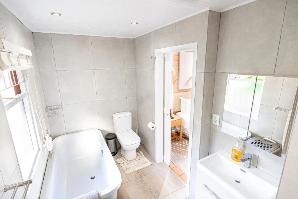 Modern bathroom with bathtub, toilet, vanity sink, and shower enclosure