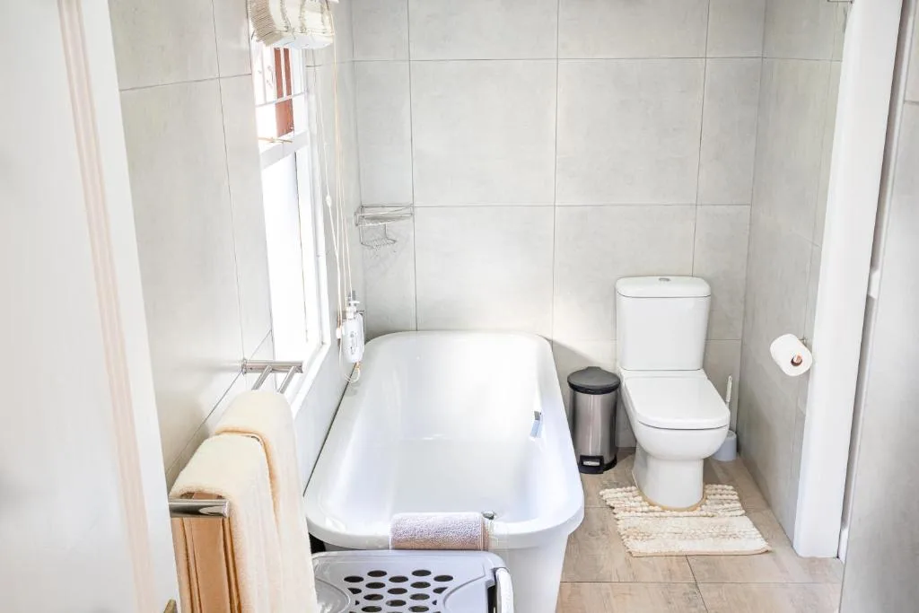 Clean bathroom with white bathtub, toilet, and tiled walls