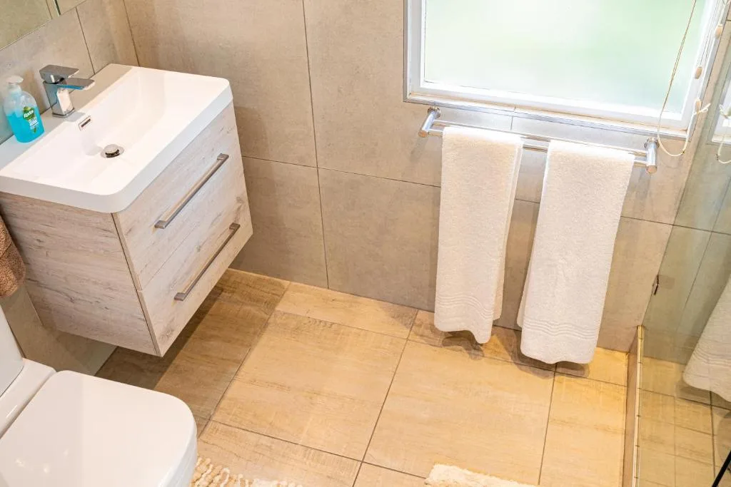 Modern bathroom with vanity sink, towel rails, toilet, and tiled shower enclosure