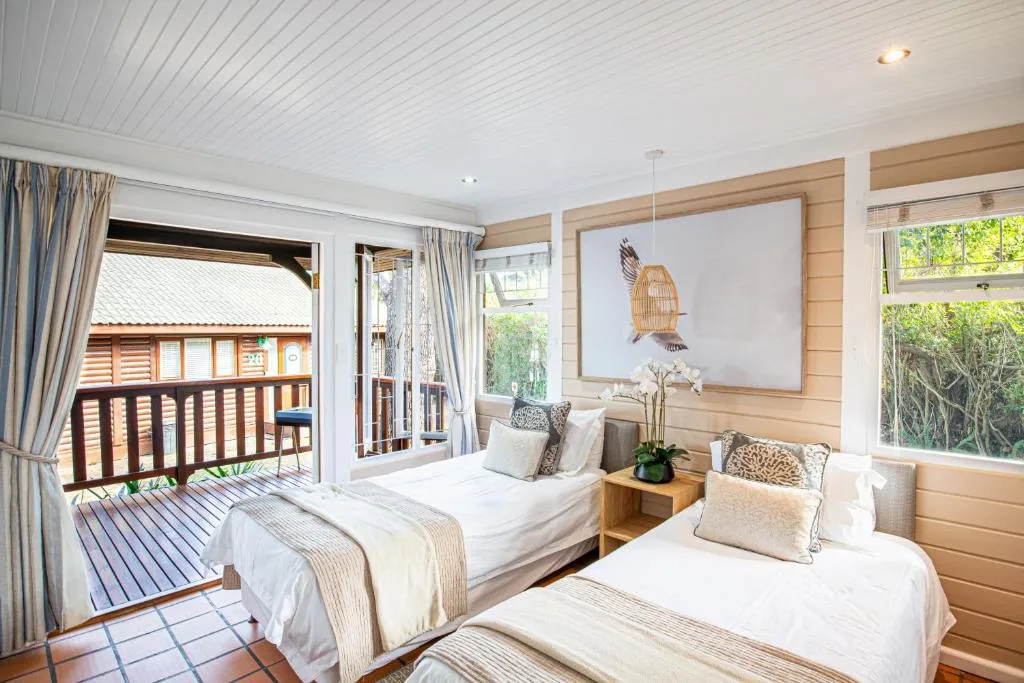 Bright bedroom with two beds, wooden accents, and deck access