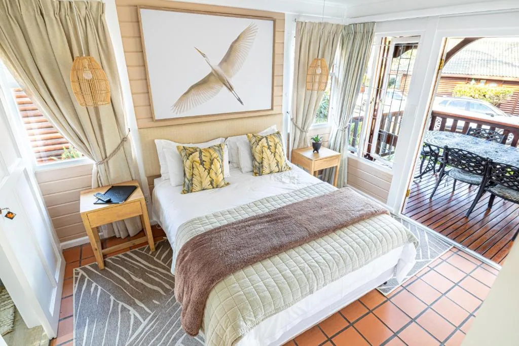Bright bedroom with queen bed, yellow patterned pillows, and deck access doors