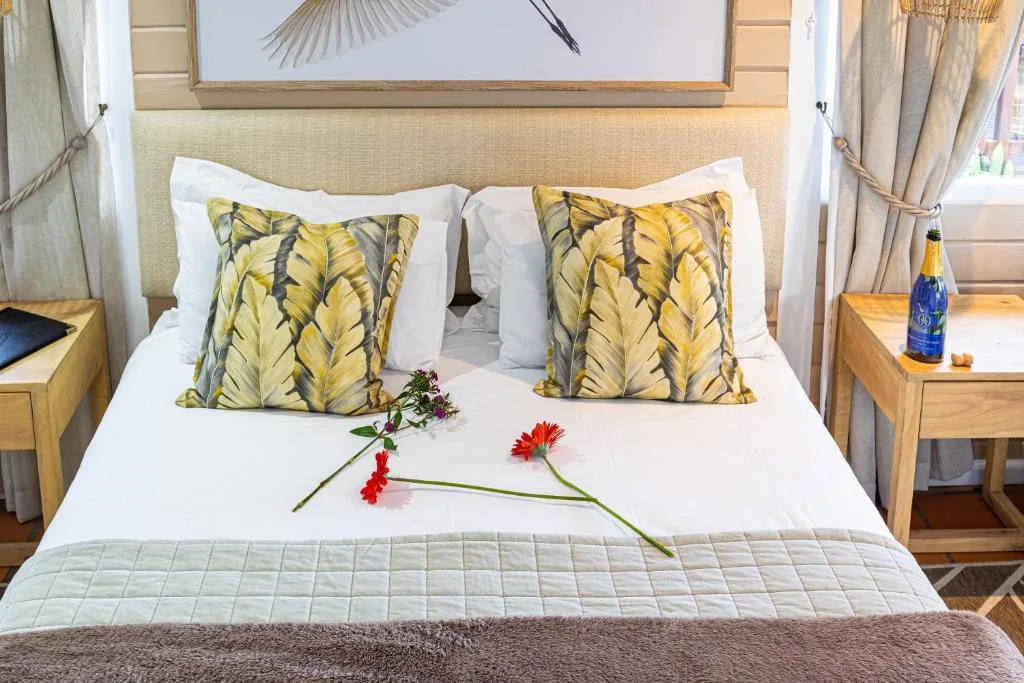 Bright bedroom with queen bed, yellow patterned pillows, fresh flowers on white bedding