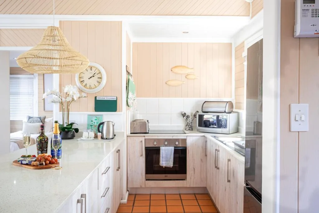 Modern kitchen with light wood cabinetry, white countertops, and stainless steel appliances