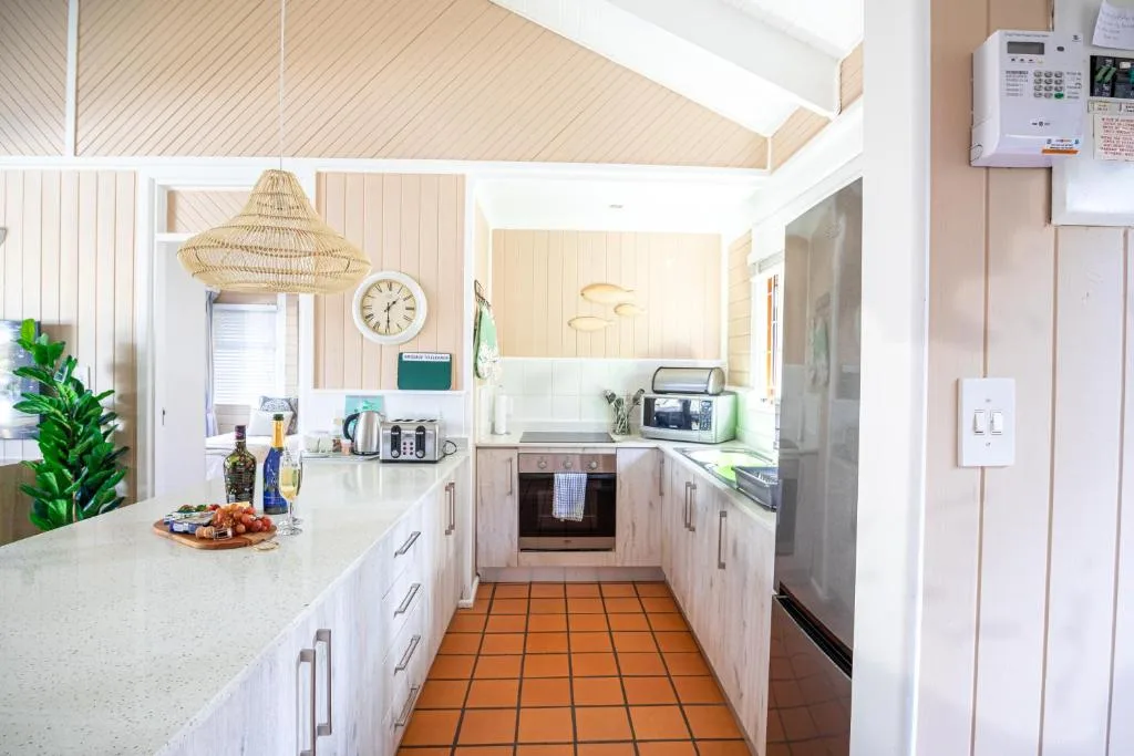 Bright modern kitchen with white cabinetry, stainless appliances, and terra cotta tile flooring