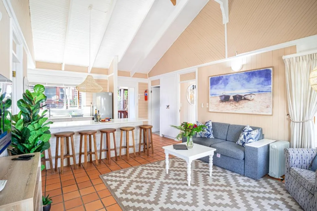 Open-plan living area with gray sofa, white coffee table, and beach artwork