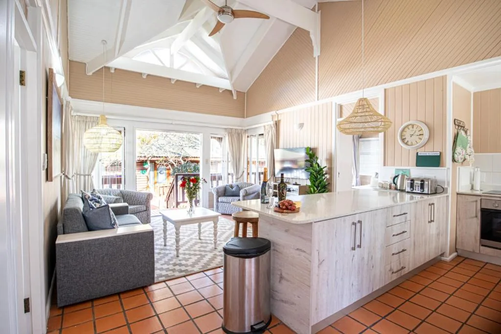 Open-plan lounge and kitchen with vaulted ceiling, comfortable seating, and garden views