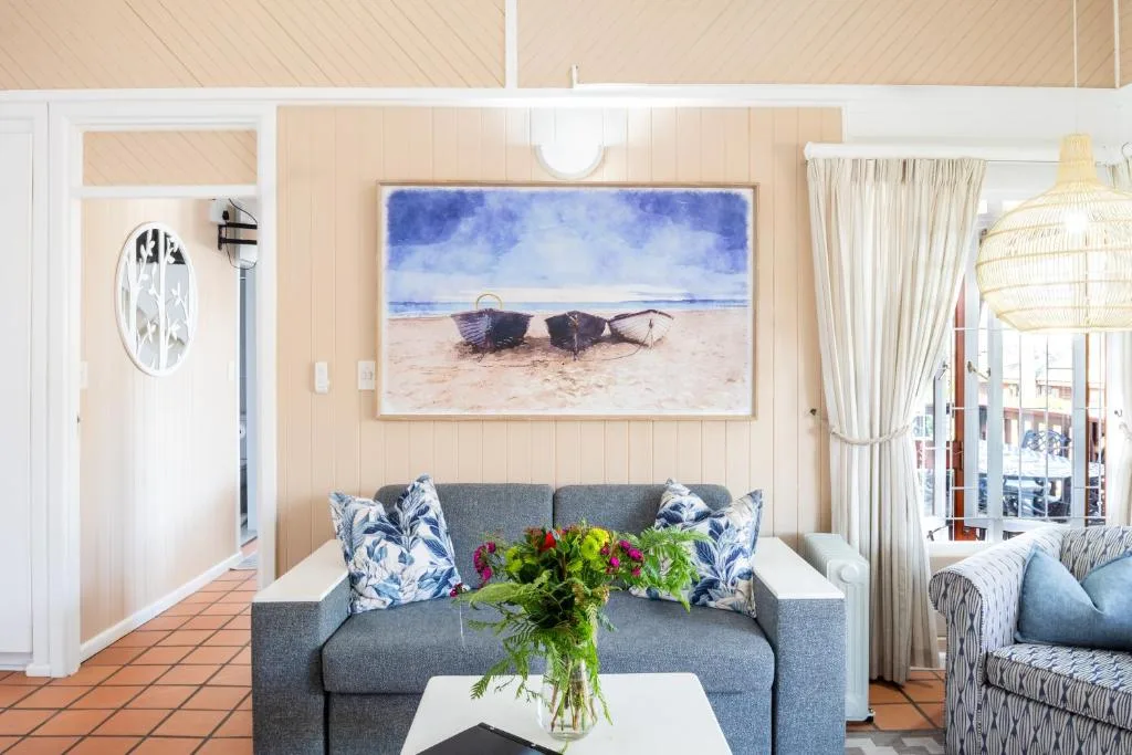 Coastal-themed lounge with gray sofa, beach artwork, and ocean views