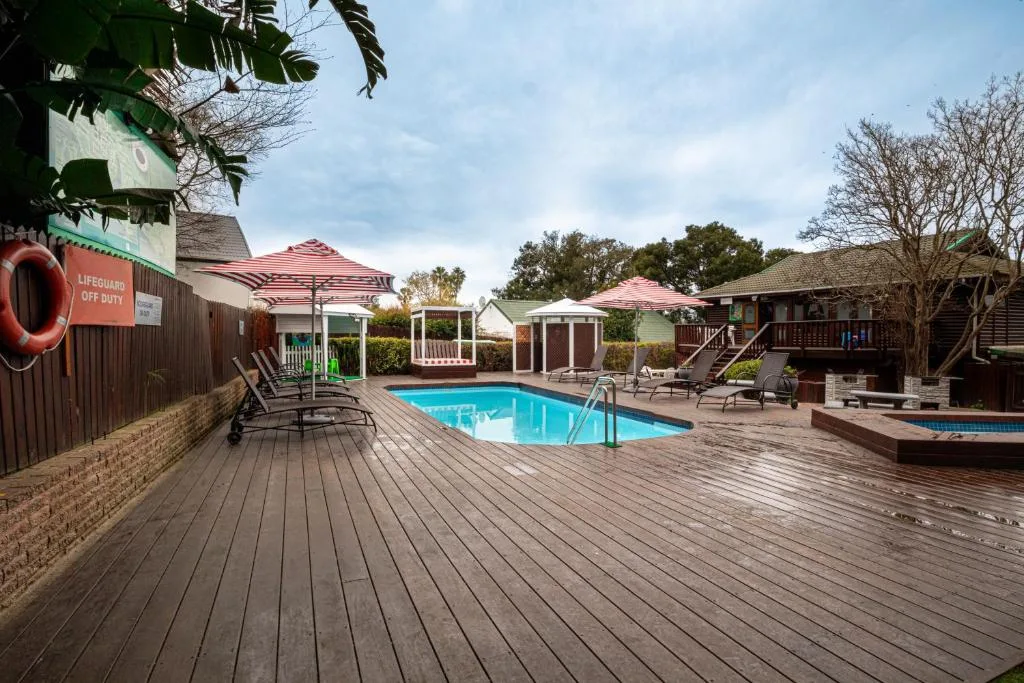 Swimming pool with wooden deck and lounge seating area surrounded by cottages